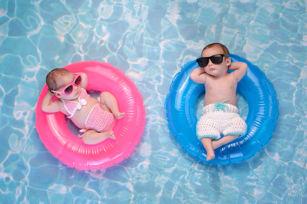 two-month-old twins floating on rings in swimming pool